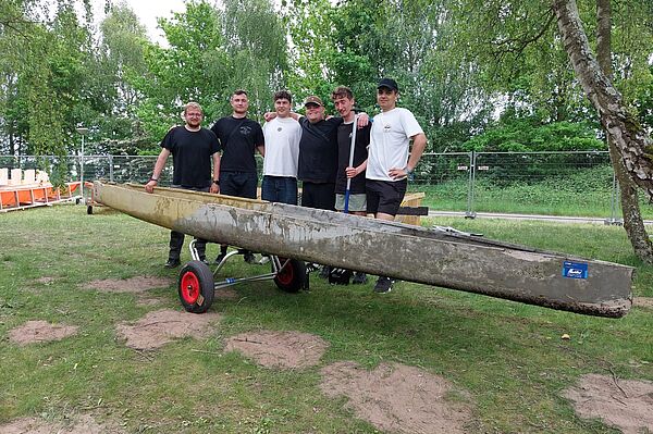 Gruppe mit Kanu aus Beton steht auf Wiese