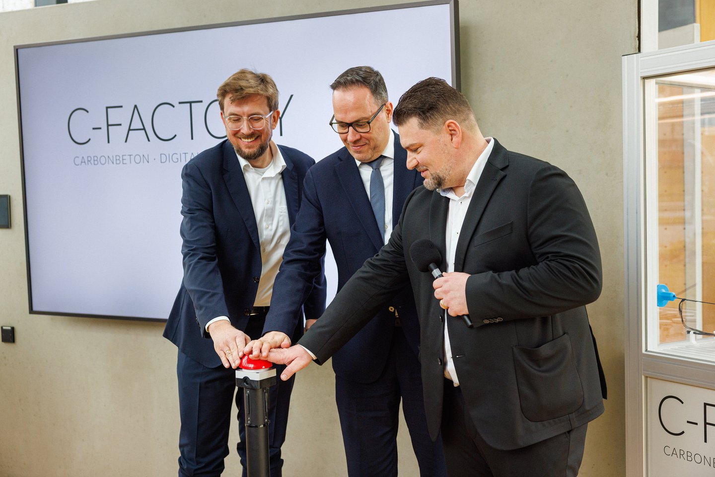 Drei Männer drücken auf roten Knopf