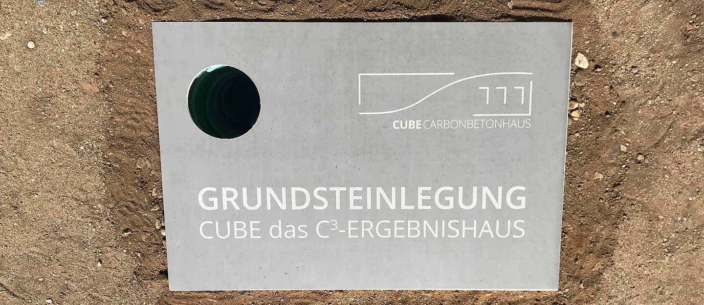 Grundstein CUBE Rechteckiger Grundstein mit einem Loch zum Einlassen der Zeitkapsel. Auf dem Grundstein steht: Grundsteinlegung. CUBE das C3-Ereignishaus.
