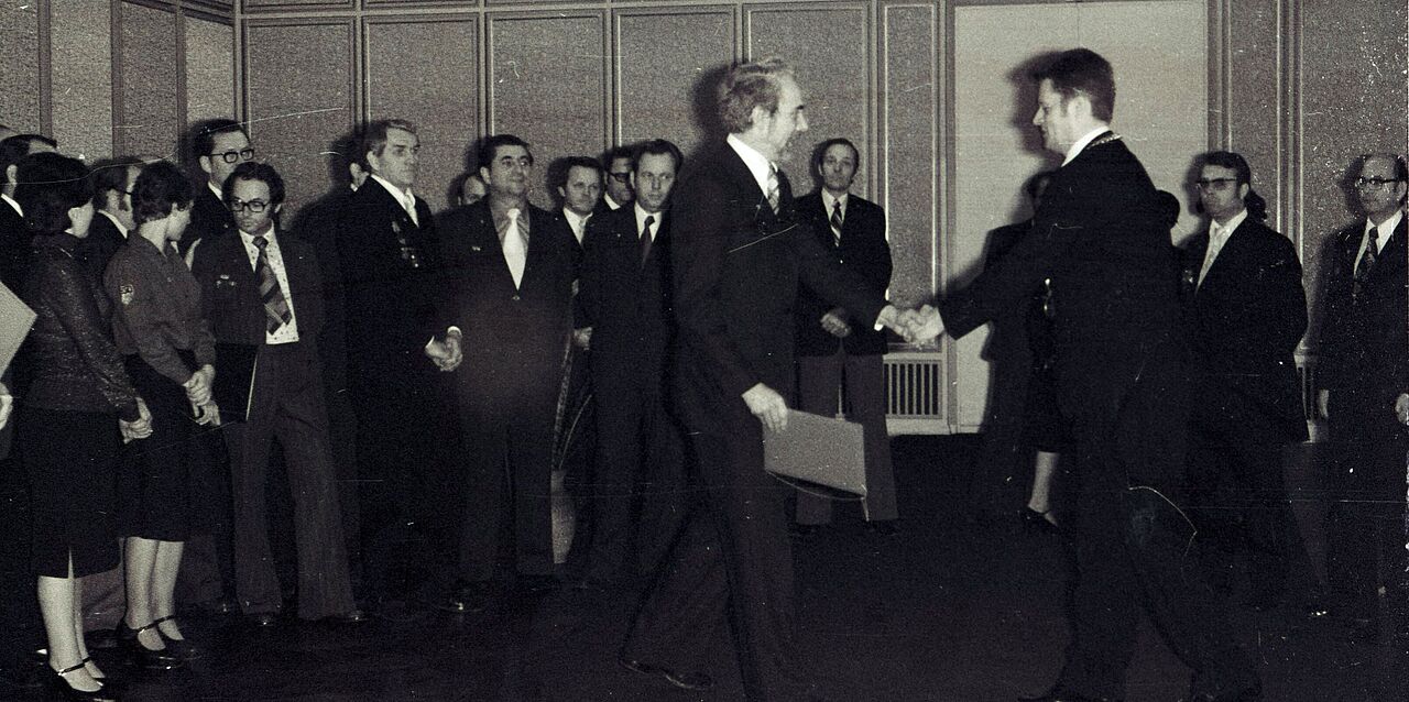 Schwarz-Weiß-Bild vom 17. Januar 1977. Dem Rektor Prof. Dr. Kurt Fiedler wird im Beisein vieler Umstehender gratuliert.