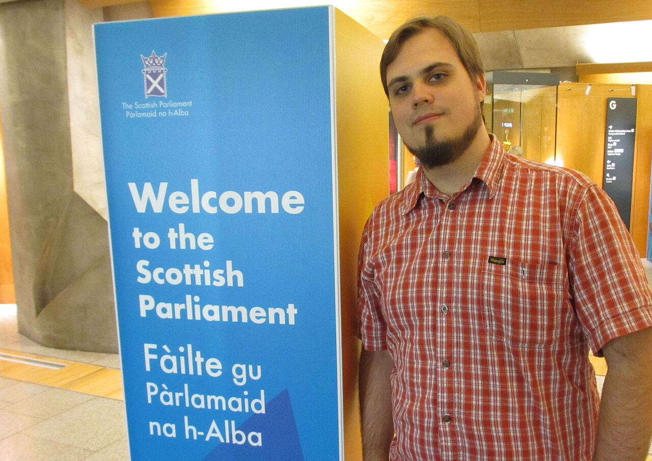Aron Schaub mit Willkommens-Wegweiser im schottischen Parlament.
