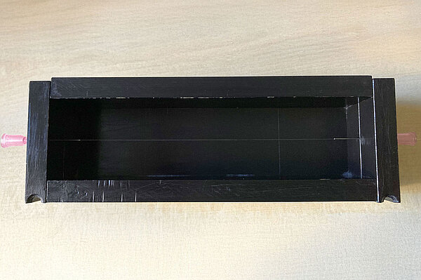 Versuchsaufbau ein schwarzer Kasten mit einer gespannten Glasfaser