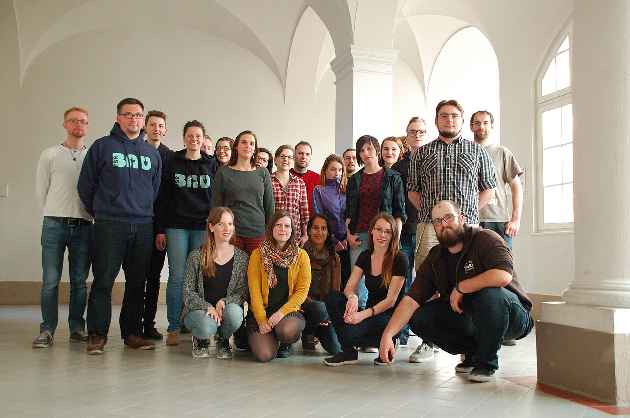 Die Mitglieder des Studierendenrates posieren für ein Gruppenfoto im Flur des Geutebrückbaus. Die vorderste Reihe kniet, der Rest steht.