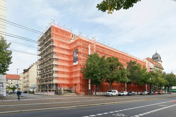 Eingerüstetes Gebäude mit orangen Planen an großer Straße