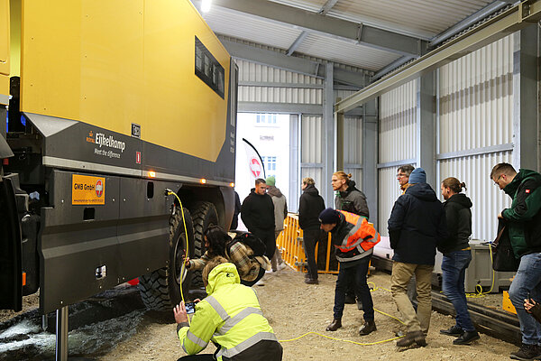 Männer und Frauen begutachten das große Fahrzeug aus der Nähe